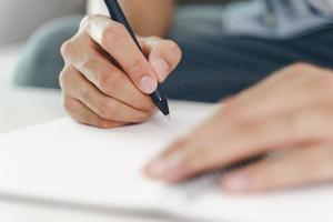 close-up das mãos do homem, escrevendo no bloco de notas, caderno usando a caneta. foto