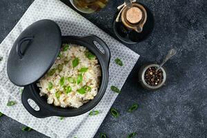 cozido arroz com frango dentro uma Panela em Sombrio cinzento fundo. topo Visão foto