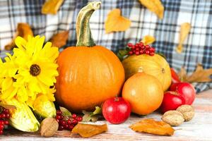 feliz Ação de graças. outono composição com abóboras, amarelo flores, vários legumes e outono folhas em uma de madeira fundo. festivo outono decoração. fechar-se. foto