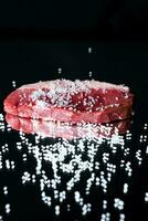 cru orgânico carne carne com alecrim, temperos, sal e vermelho Pimenta em Preto fundo foto