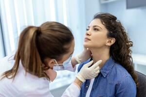 medicamento, cuidados de saúde e médico exame conceito - médico ou enfermeira verificação pacientes amígdalas às hospital. endocrinologista examinando garganta do jovem mulher dentro clínica foto