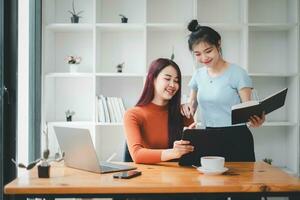 dois empresária trabalhando juntos em digital tábua. criativo fêmea executivos encontro dentro a escritório usando digital tábua e sorridente. foto