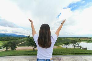 uma jovem mulher carrinhos com dela braços estendido em uma sacada acima uma lindo chá plantação para simbolizar dela felicidade dentro viajando e relaxante durante a feriados. feriado felicidade conceito foto