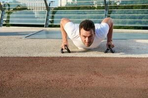 frente Visão do uma determinado desportista fazendo flexões , bombeamento peito e ombros músculos durante manhã exercite-se ar livre. manter seu corpo em forma e apreciar verão momentos foto