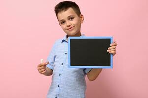 isolado retrato em Rosa fundo do uma estudante com giz e quadro-negro dentro dele mãos. costas para escola. conceitos foto