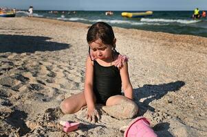 verão período de férias. adorável criança pequena menina jogando com de praia brinquedos em a arenoso de praia. verão feriados conceito. ativo estilos de vida e feliz verão Férias foto