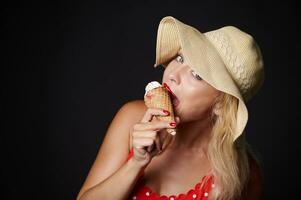 atraente europeu Loiras mulher dentro verão chapéu segurando uma delicioso sorvete dentro dela mãos e sorrisos com lindo cheio de dentes sorrir olhando às Câmera, isolado sobre Preto fundo com cópia de de Anúncios espaço foto