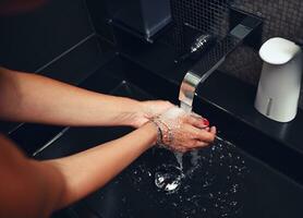 a sobrecarga Visão do irreconhecível mulher lavando mãos debaixo uma jato do corrida água. fechar-se, cortada imagem foto