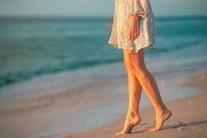 pernas femininas na praia closeup. mulher de vestido andando na praia foto