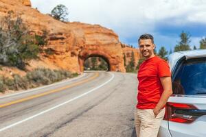 jovem caucasiano homem dentro fundo do natural pedra arco ponte dentro a vermelho desfiladeiro nacional parque dentro utah, EUA foto