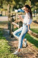 jovem mulher usando Móvel telefone ao ar livre dentro a parque foto