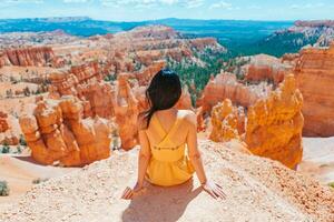 caminhante mulher dentro Bryce desfiladeiro em repouso desfrutando Visão dentro lindo natureza panorama com capuzes, pináculos e pináculos Rocha formações dentro Utah foto