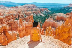 caminhante mulher dentro Bryce desfiladeiro em repouso desfrutando Visão dentro lindo natureza panorama com capuzes, pináculos e pináculos Rocha formações dentro Utah foto