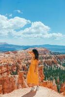 caminhante mulher dentro Bryce desfiladeiro em repouso desfrutando Visão dentro lindo natureza panorama com capuzes, pináculos e pináculos Rocha formações dentro Utah foto