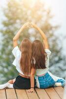 costas Visão do jovem meninas sentar em uma terraço às uma altura dentro a montanhas contra a pano de fundo do névoa e montanhas foto