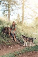 jovem mulher dentro Palha chapéu caminhando com dela cachorro dentro a floresta. Sol verão dia com a cachorro em a caminho. foto