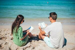 jovem casal lendo livros em tropical de praia foto