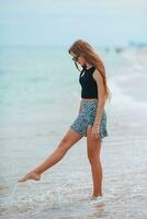 adorável adolescente se diverte na praia tropical durante as férias em águas rasas foto