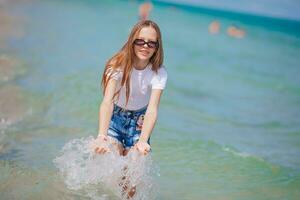 menina feliz espirrando e correndo na água azul-turquesa foto