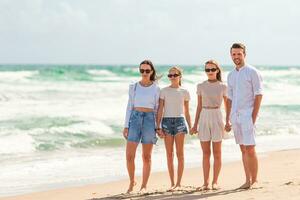 pais jovens e duas adolescentes em férias na praia foto