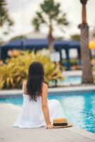 jovem lindo mulher desfrutando verão período de férias dentro infinidade luxo natação piscina foto