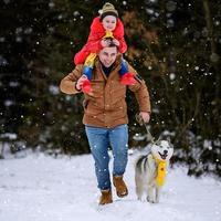 husky em um lenço amarelo com o proprietário, caminhando na floresta de inverno. foto