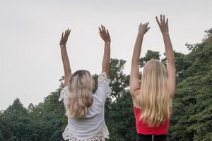 duas mulheres em pé e levantam as mãos no parque. melhores amigos foto