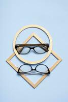 óculos para visão em uma azul fundo com dourado formas. ótico loja, visão teste, à moda óculos conceito foto