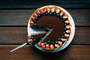 delicioso bolo de chocolate com frutas vermelhas e cobertura, vista de cima foto