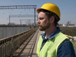 um homem com barba e bigode em um capacete está em uma ponte foto