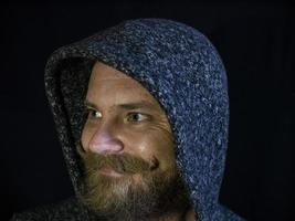 retrato de um homem com barba no capuz e um rosto sorridente