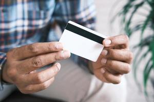 close-up da mão da pessoa segurando o cartão de crédito