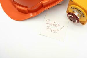 laranja segurança chapéu com mensagem segurança primeiro e emergência Pare botão isolado em branco fundo. segurança primeiro conceito. foto