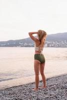 jovem em pé na praia pedregosa olhando para o mar