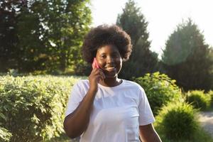 mulher afro-americana feliz com um telefone na rua no verão foto
