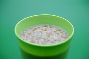 verde plástico copo contendo cereal beber isolado em verde fundo foto