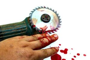 mão e disco de serra circular com sangue no fundo branco foto