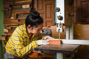 mulheres em pé é artesanato, corte de madeira em uma bancada de trabalho foto