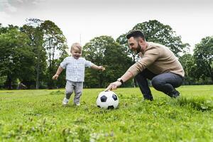 feliz pai jogando futebol com filho dentro uma parque foto