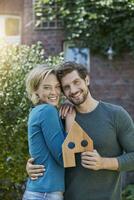 retrato do feliz casal dentro frente do seus casa com casa modelo foto