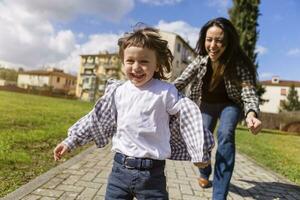 mãe corrida atrás feliz criança pequena filho em uma caminho foto