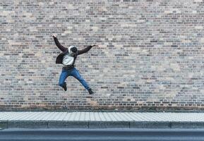 jovem homem pulando dentro frente do tijolo parede foto