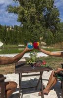 casal brindando com ninho de coquetel de frutas na piscina, múrcia, espanha foto