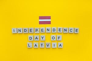 novembro 18, independência dia do Letônia, a bandeira do Letônia, uma minimalista bandeira com a inscrição dentro de madeira cartas em a laranja fundo foto