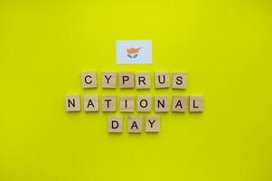 Outubro 1, independência dia dentro Chipre, Chipre nacional dia, bandeira do Chipre, minimalista bandeira com a inscrição dentro de madeira cartas em uma amarelo fundo foto
