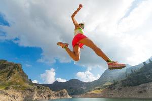 pulando garota enquanto ele corre perto de um lago na montanha foto