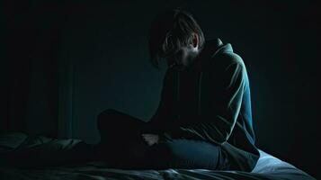 depressivo homem sentado cabeça dentro mãos em a cama dentro a Sombrio quarto, solitário e infeliz conceito. generativo ai foto