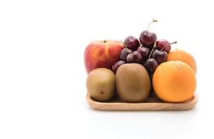 frutas misturadas em placa de madeira no fundo branco foto