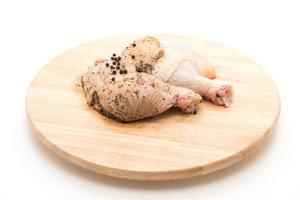 Coxa de frango marinado com molho, pimenta preta, alho e pimenta seca na tábua de madeira