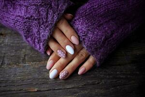 mulheres é mãos com uma lindo manicure, dentro uma tolet tricotado suéter em uma de madeira fundo em. outono tendência, polonês bege e branco polca pontos em unhas com gel polonês, shellac. foto